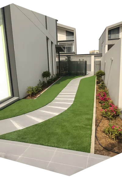 Dubai villa garden landscaping with artificial grass, curved stone pathway, flower beds, and modern outdoor design