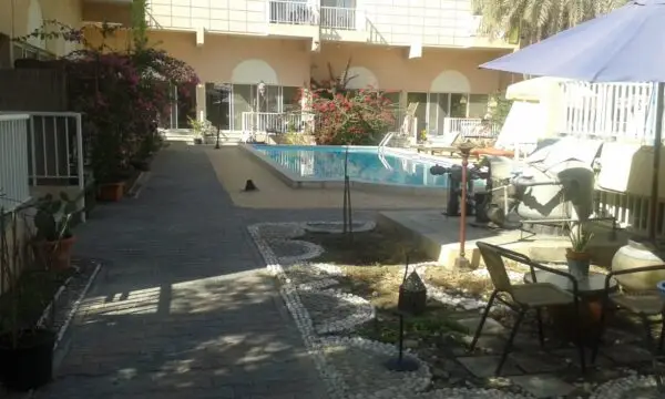 Residential poolside with landscaped pathway, plants, and seating area for outdoor relaxation.