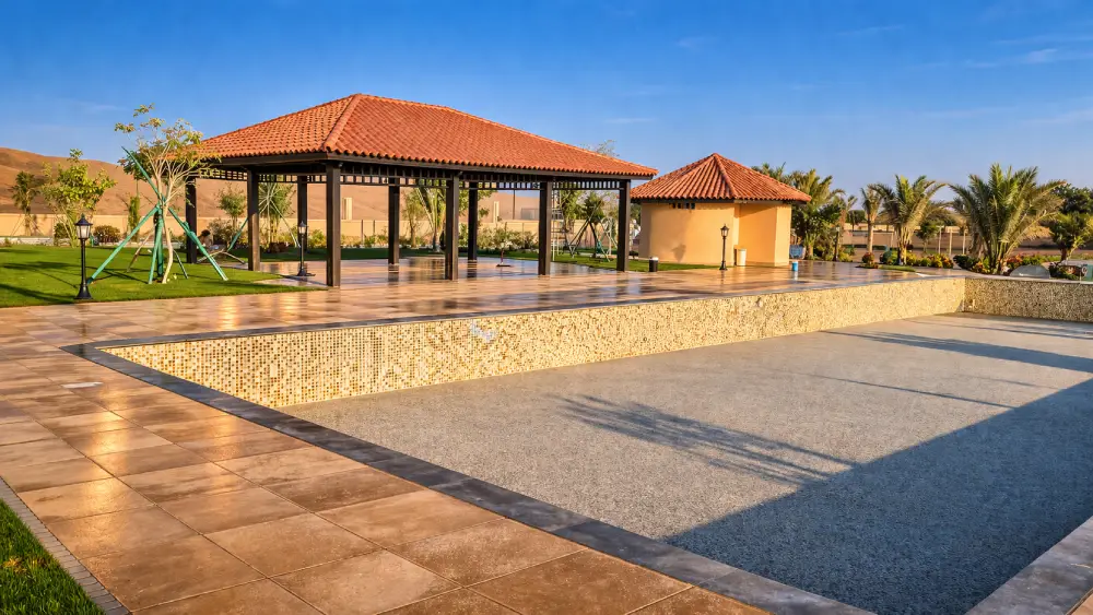Poolside landscaping with gazebo pavilion, tiled patio and outdoor seating area in Al Ain UAE