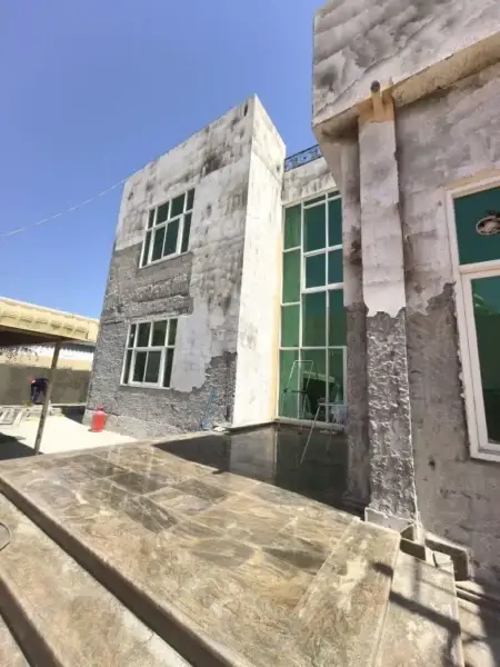 Exterior of a house with partially stripped and weathered walls undergoing renovation.