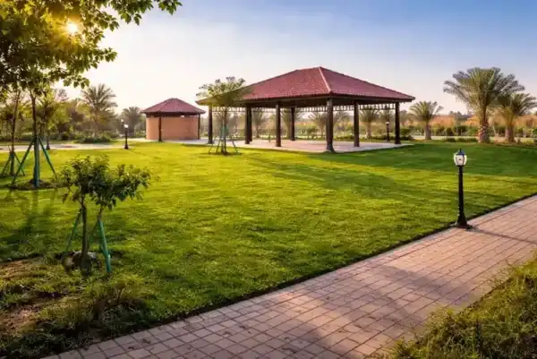 Completed landscaped garden with green lawn, gazebo pavilion, pathway and trees in Al Ain UAE
