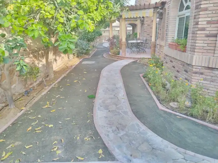 Completed natural stone pathway winding through a Dubai villa garden toward a pergola seating area