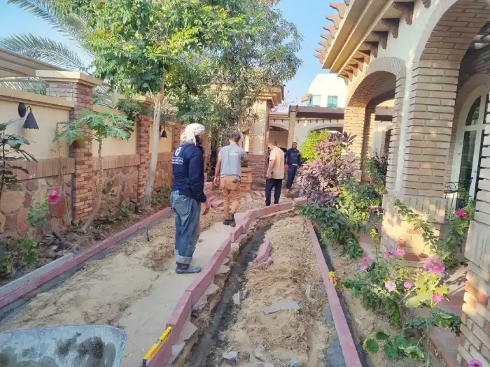 Landscaping team setting out curved brick edging for a villa garden pathway in Jumeirah Dubai