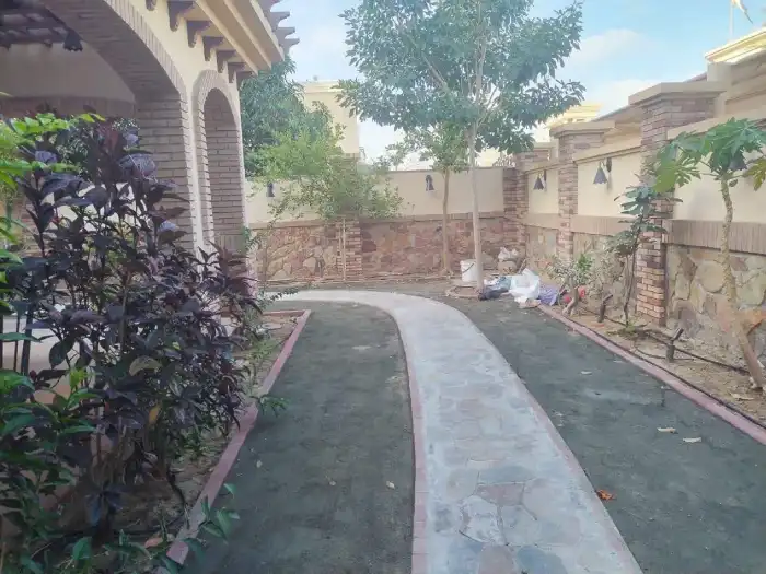 Curved stone garden path taking shape with brick edging and existing planted trees in a Jumeirah Dubai villa landscape
